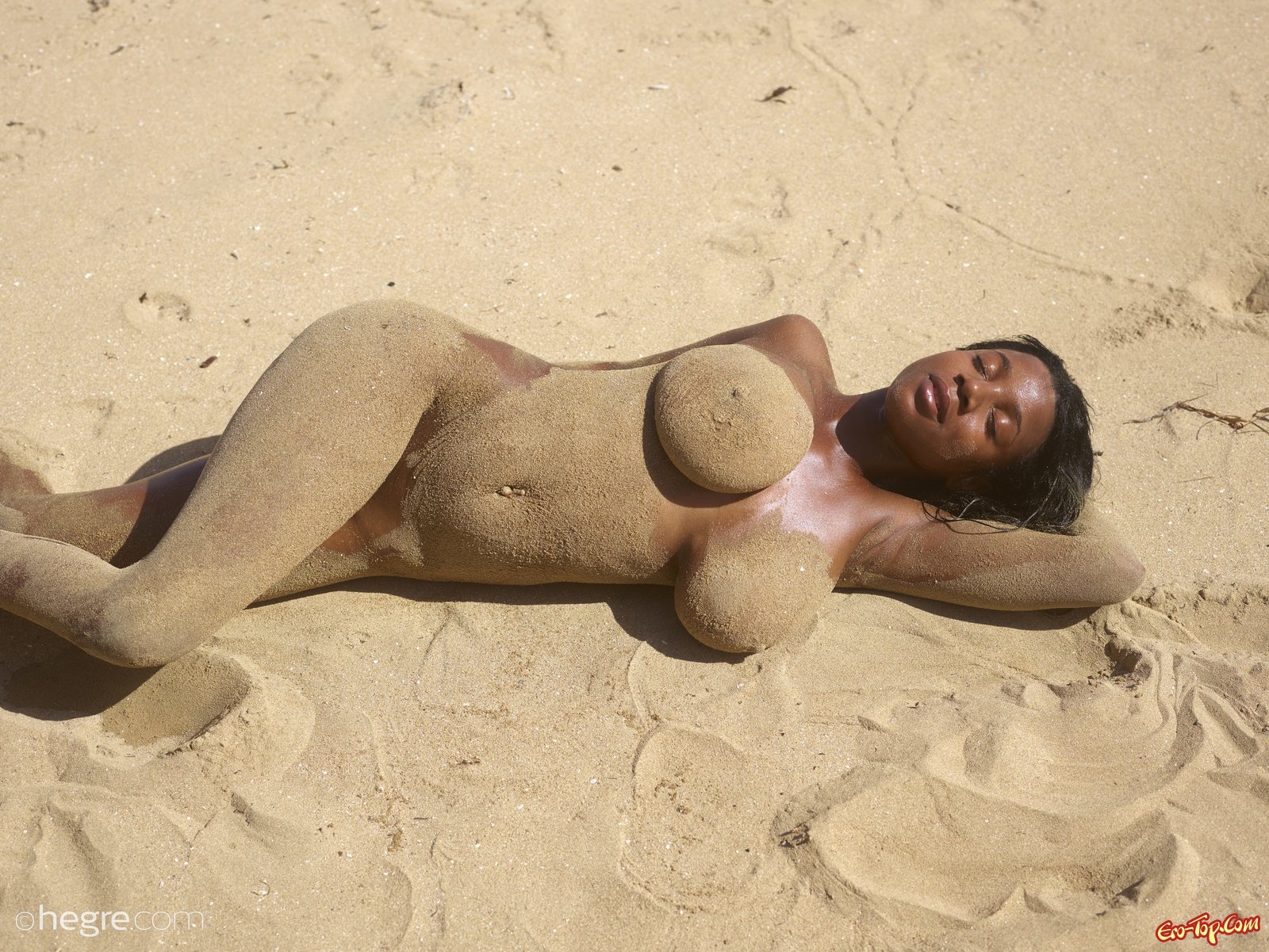Негритянка с большой грудью валяется на пляже